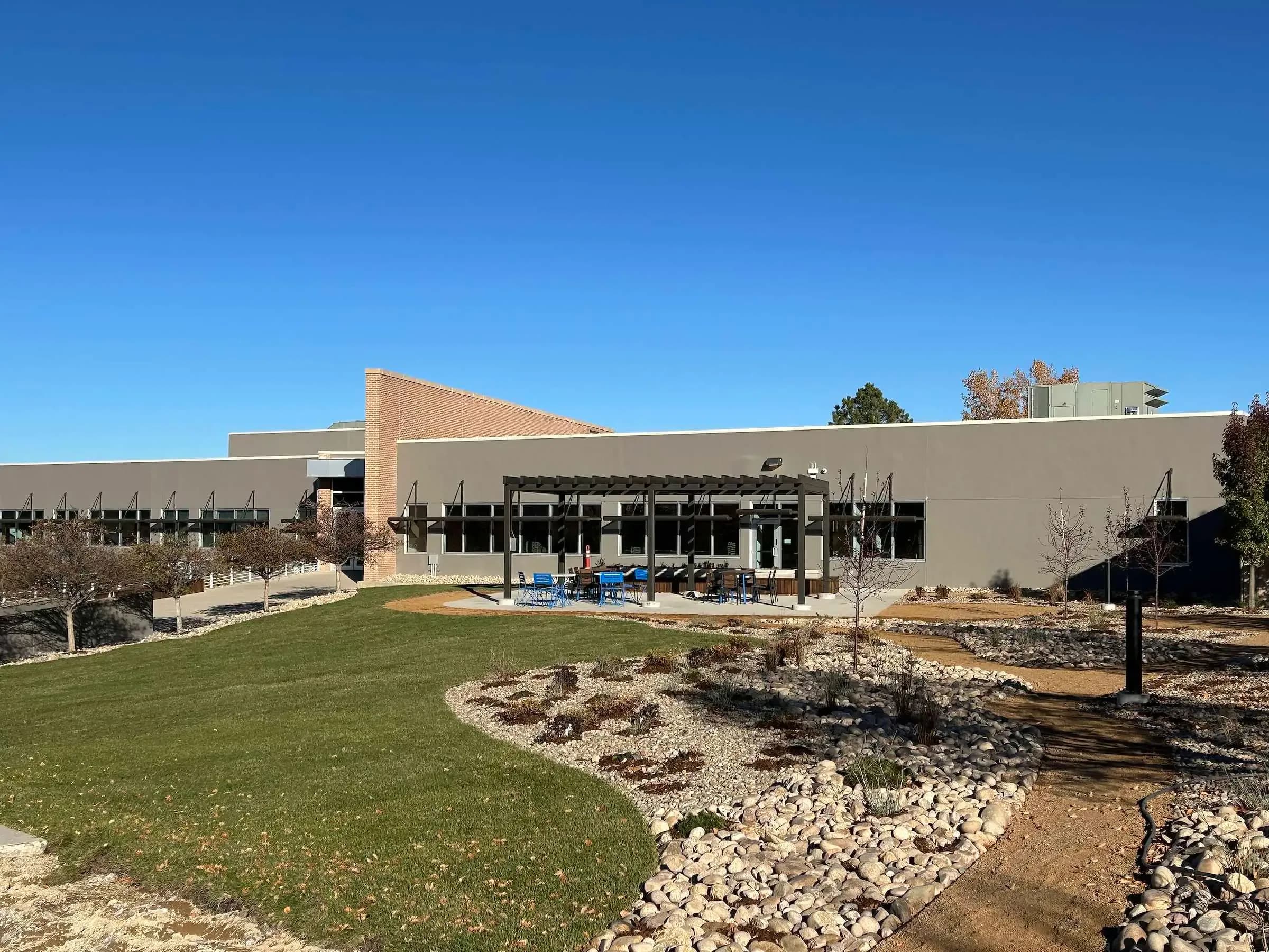 A building courtyard with a pergola patio, new lawn and river rock landscaping.