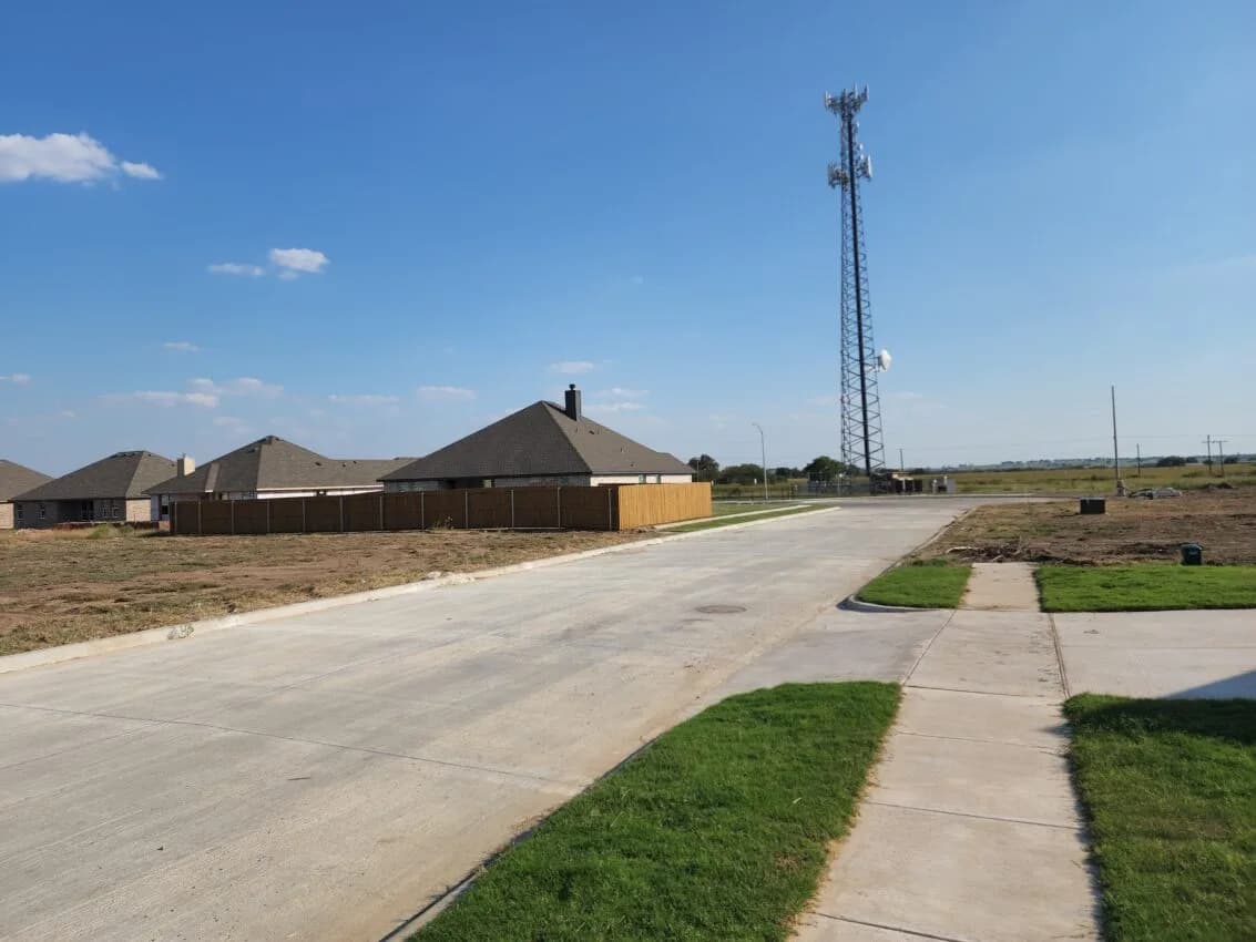 New concrete residential street with sidewalks and sod beside finished homes and graded lots