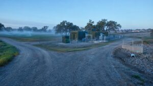 Operational package wastewater treatment facility in Texas with treated effluent flowing to irrigation reuse on one side and a capped discharge outfall pipe on the other side representing the 210E backup discharge permit dual pathway strategy