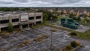 Vacant industrial building at a Texas mixed-use development site with a for-lease sign visible and a connected wastewater treatment facility in the background illustrating the compliance gap created when a 210E reuse user exits