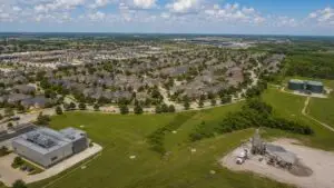Aerial view of a mixed-use Texas development showing residential buildings, a data center, and commercial retail all connected to a single wastewater collection system feeding one 210E-authorized treatment facility 1