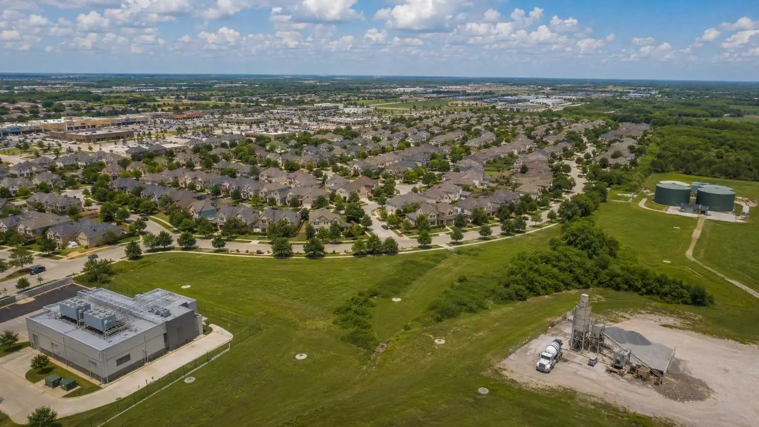 Aerial view of a mixed-use Texas development showing residential buildings, a data center, and commercial retail all connected to a single wastewater collection system feeding one 210E-authorized treatment facility 1