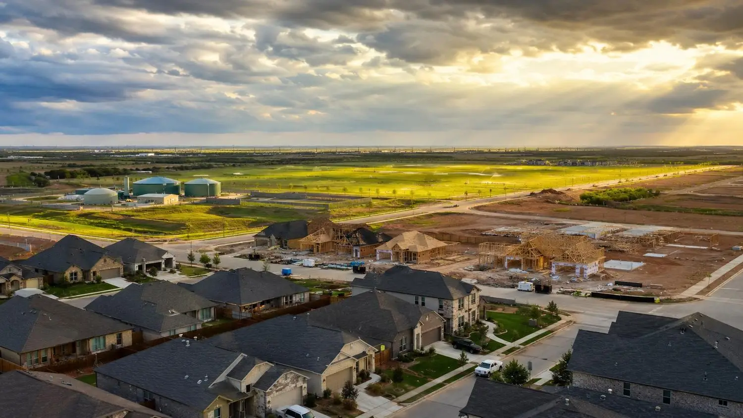 Aerial perspective of a large master-planned Texas subdivision with hundreds of homes at various construction stages and a private wastewater treatment facility at the edge of the development illustrating long-term dual permit risk management