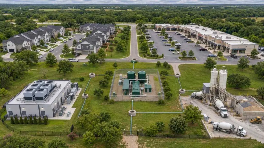 Aerial view of a mixed-use Texas development showing residential buildings, a data center, and commercial retail all connected to a single wastewater collection system feeding one 210E-authorized treatment facility