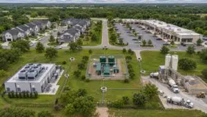 Aerial view of a mixed-use Texas development showing residential buildings, a data center, and commercial retail all connected to a single wastewater collection system feeding one 210E-authorized treatment facility