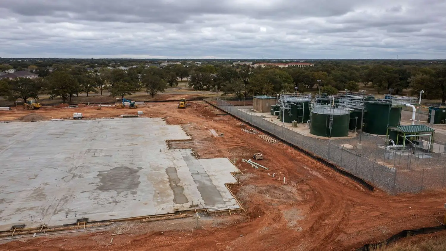 Wastewater engineer and architect reviewing overlapping site plan and wastewater infrastructure layout at a Texas development project showing treatment plant siting, lift station locations, and force main routing coordinated with building footprints