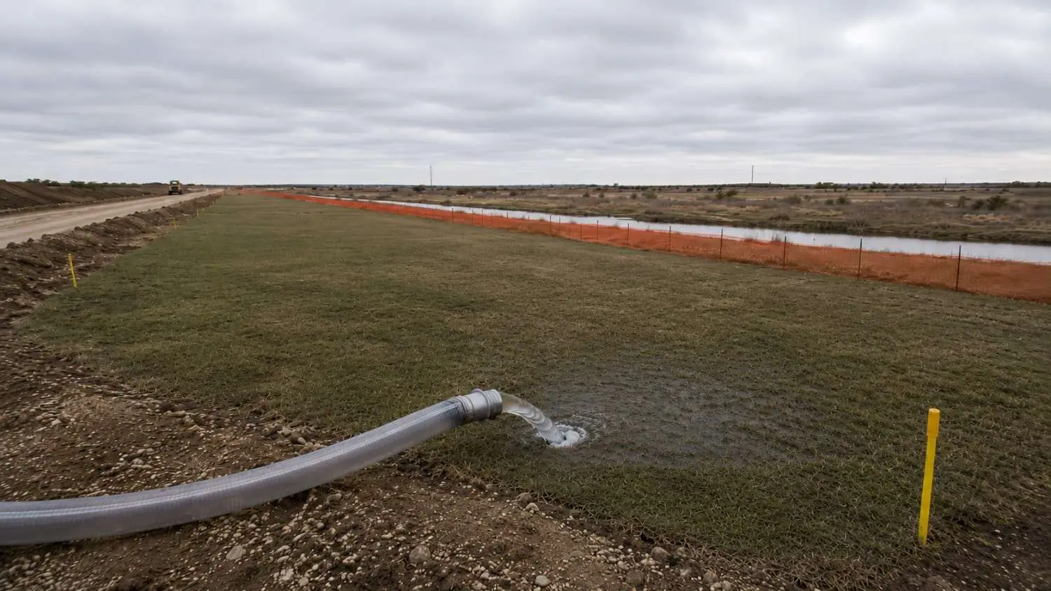 Test water from a Texas pipeline hydrostatic pressure test being discharged at a controlled rate to a designated pervious grassy disposal area on the construction site showing the land application disposal method that avoids TCEQ surface water discharge authorization requirements