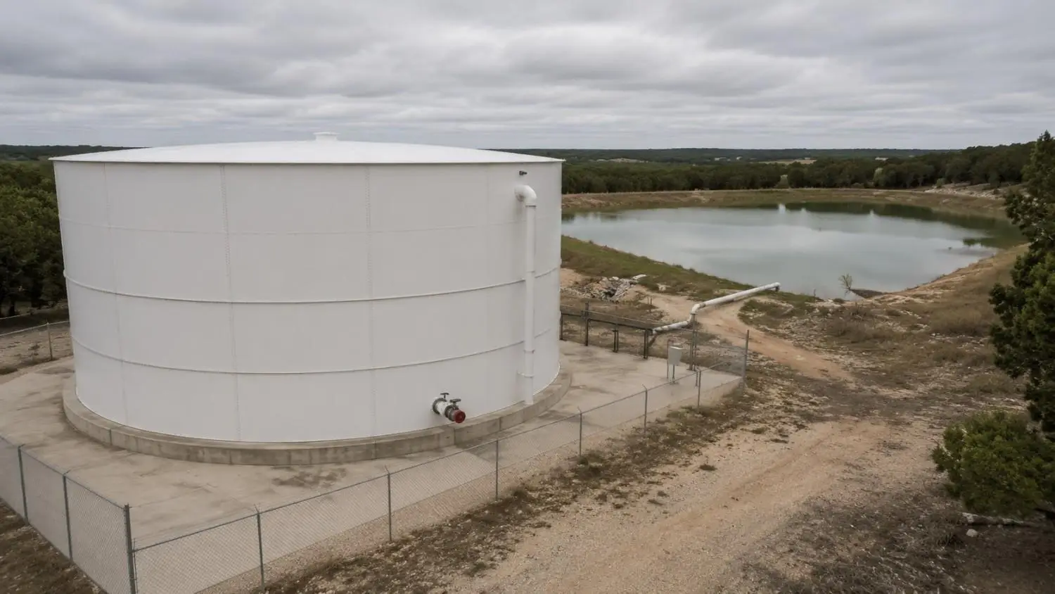 Ground-level wide shot of a large on-site fire suppression storage tank installation at a rural Texas commercial development site designed by Modern Engineering Solutions under NFPA 1142.