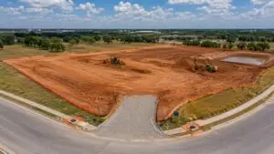 Active Texas construction site showing freshly graded bare red clay soil with erosion and sediment controls including silt fence perimeter, stabilized construction entrance, and inlet protection devices installed before land disturbance representing TXR150000 Construction General Permit compliance requirements
