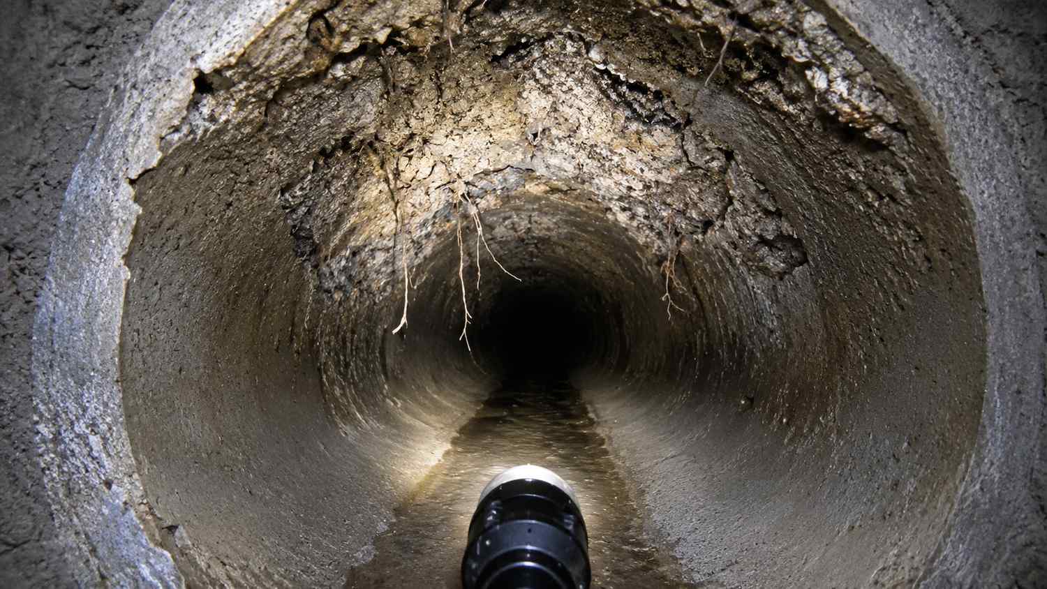 Cross-section of a deteriorated Florida concrete sewer pipe showing hydrogen sulfide crown corrosion and structural degradation evaluated by MES.